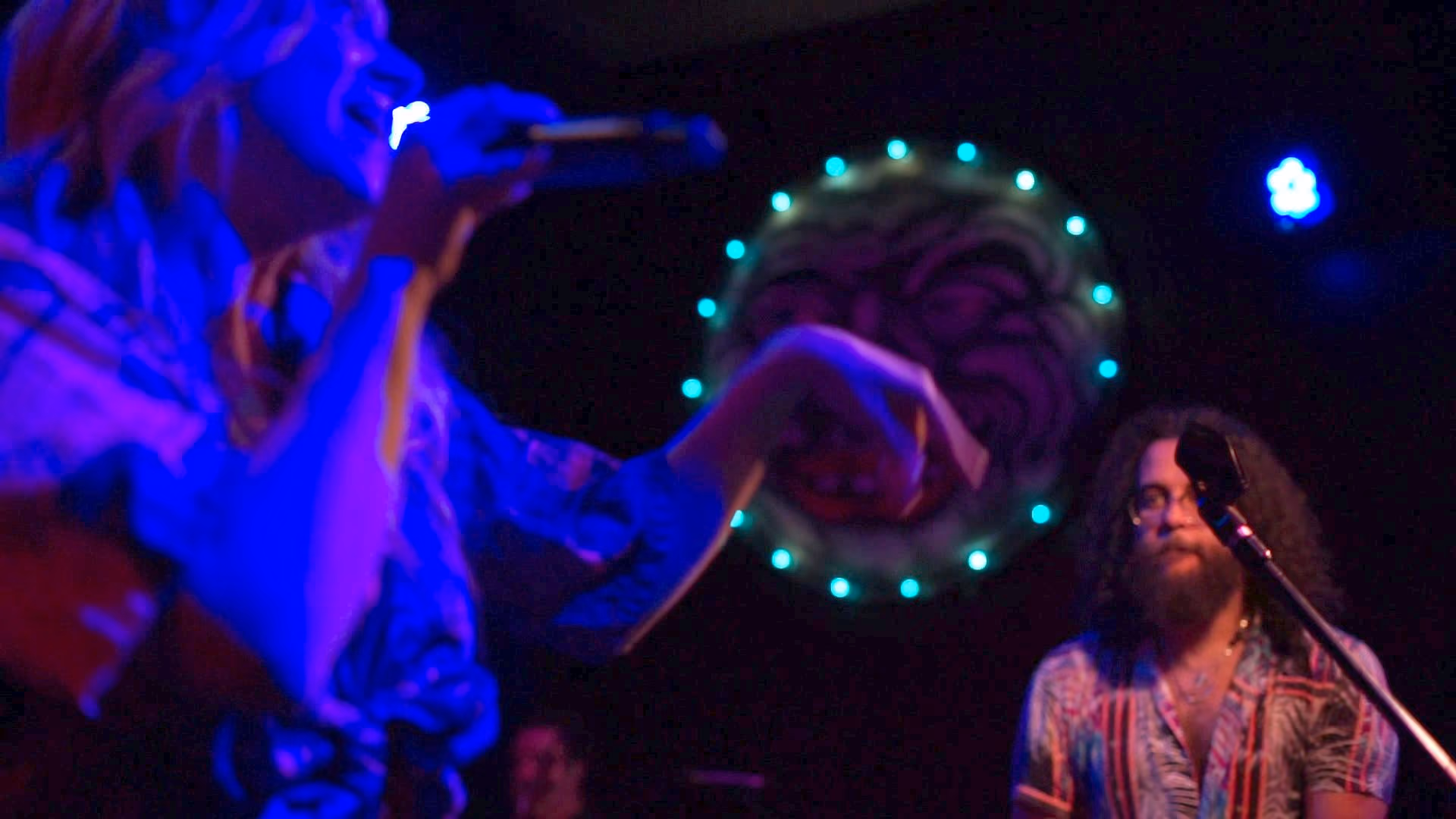 Singer under blue light in front of a ring of stage lights