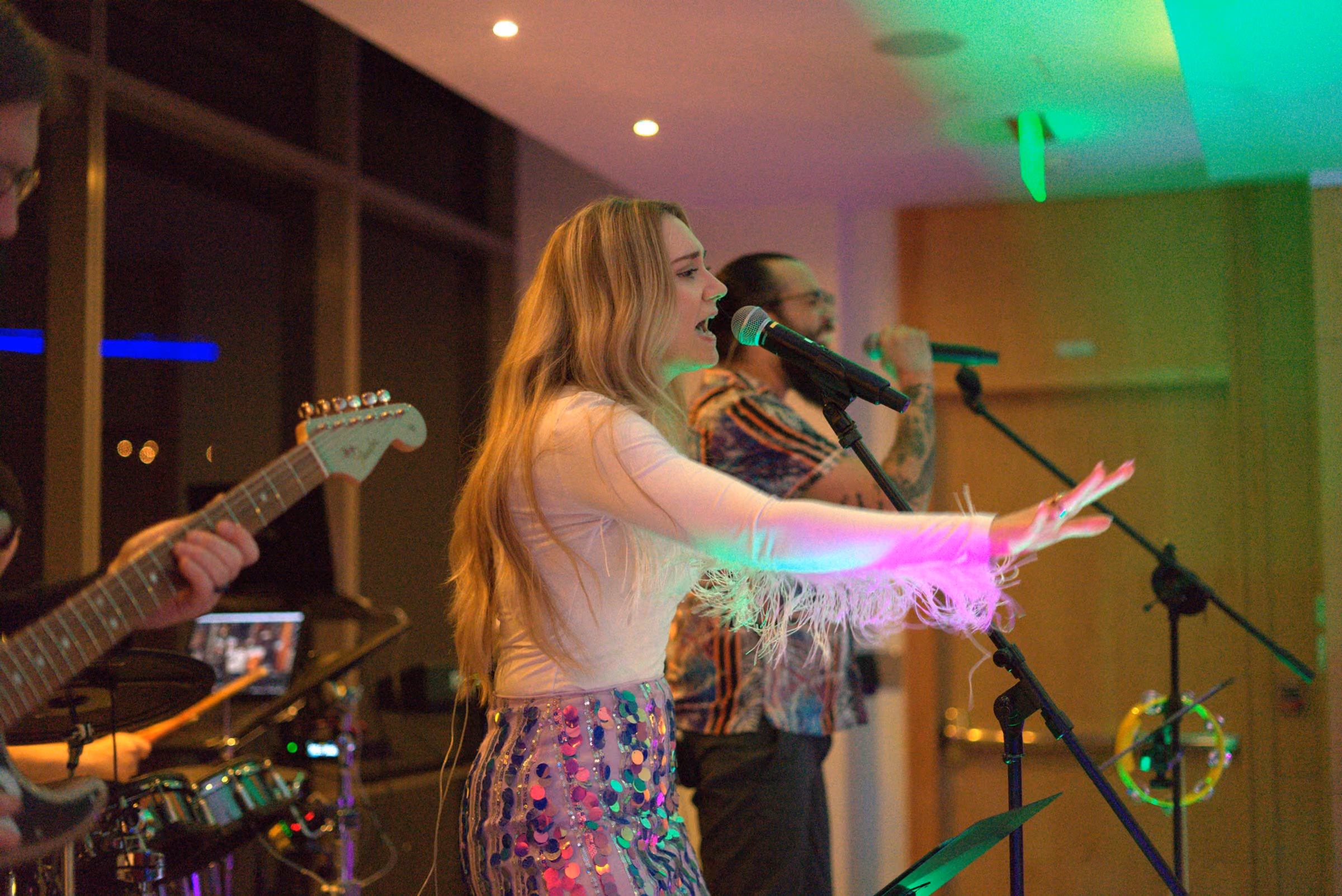 Singer at the microphone with a pink light streak across the frame